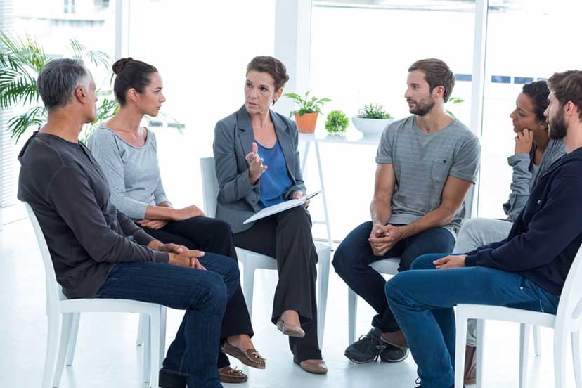 Group-therapy-in-session-sitting-in-a-circle-in-a-bright-room