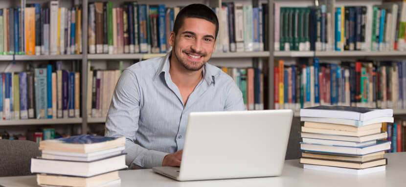 Smiling-Man-With-Laptop-And-Books-At-Library
