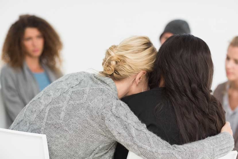 Women-embracing-in-rehab-group-at-therapy-session