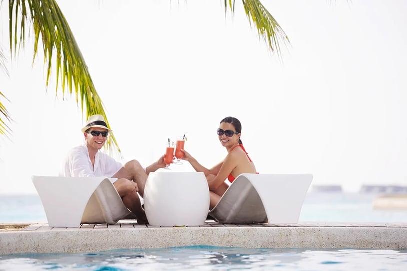 happy vacationing couple relaxing by the pool