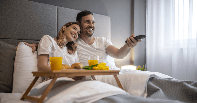 happy-couple-watching-tv-in-hotel-room