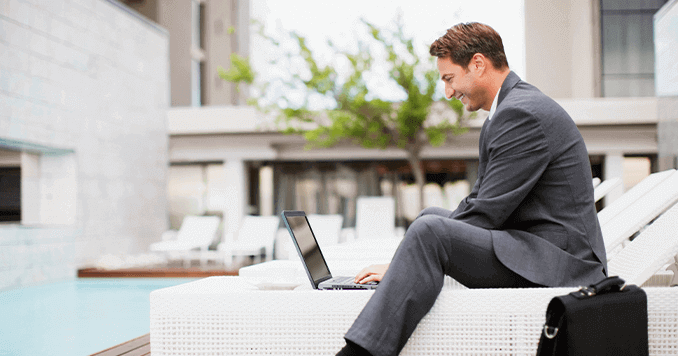 happy-guest-sitting-poolside-on-computer 