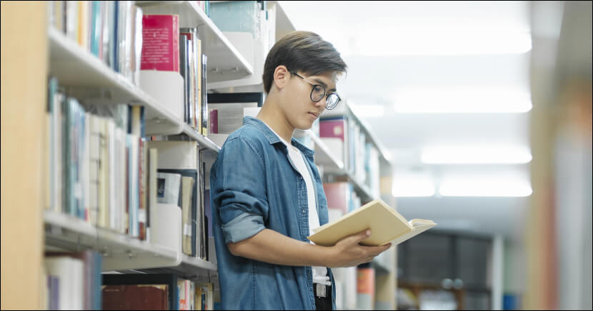 student-looking-at-book-in-library