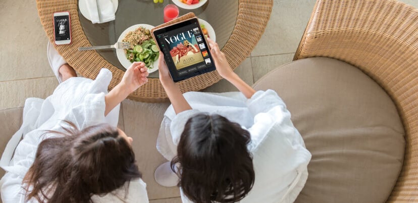 two-women-using-pressreader-by-hotel-lounge 