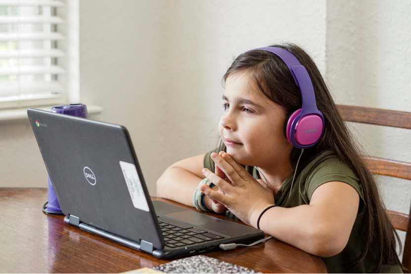 young girl with headphones looking at a computer