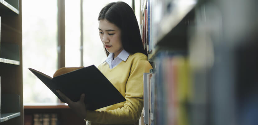 young-student-reading-book-at-library